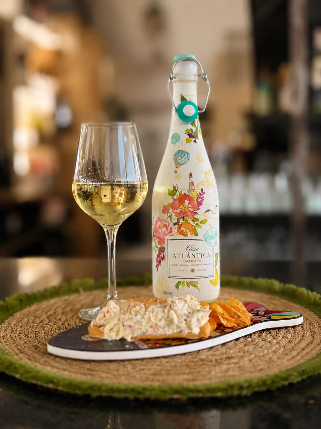 Flasche Sangría und ein Glas Weißwein neben einer Marinera und Kartoffelchips
