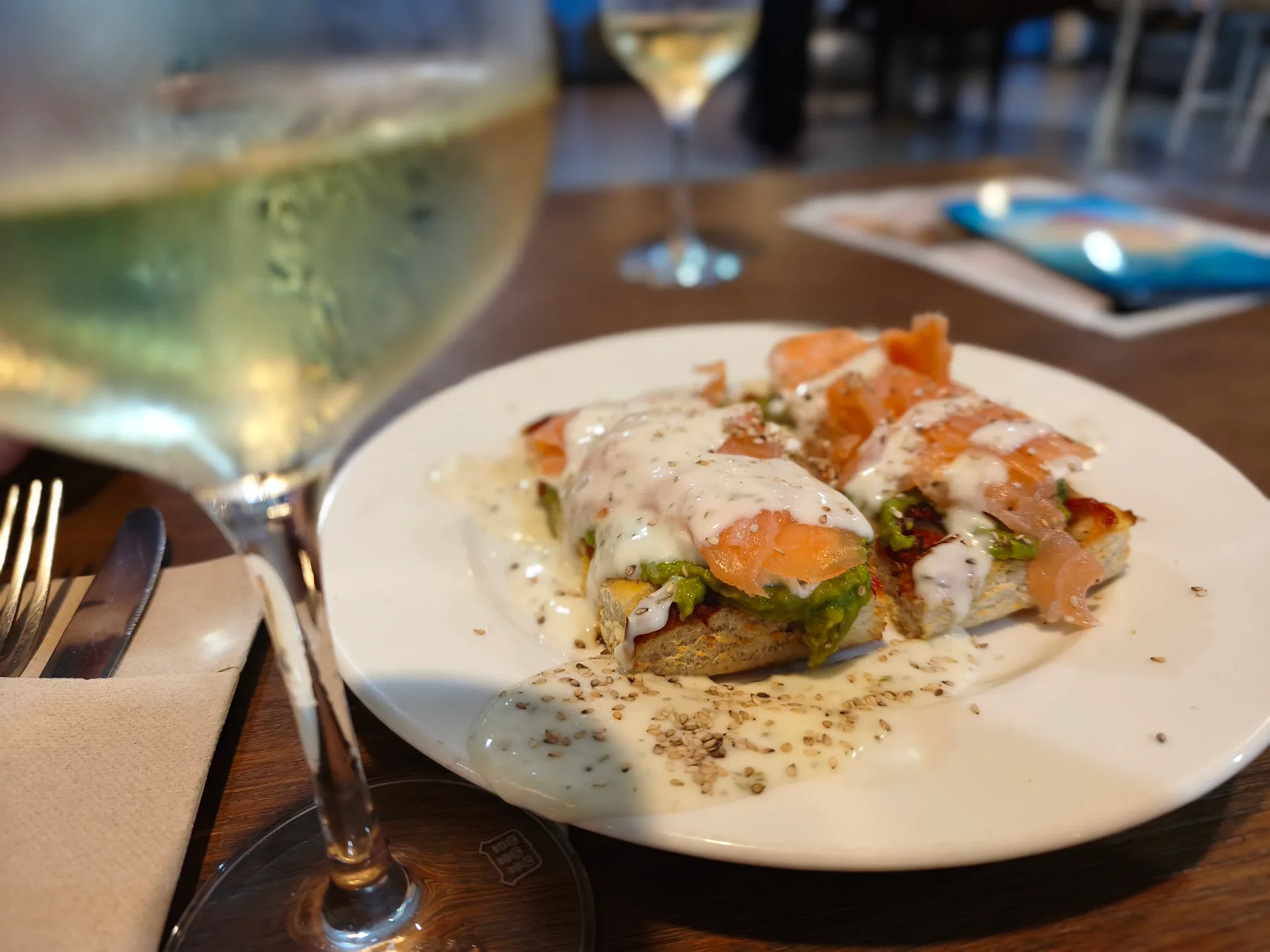 Röstbrot mit Lachs und Avocado, dazu ein Glas Weißwein